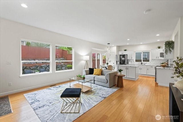 living area featuring recessed lighting, baseboards, and light wood-style floors