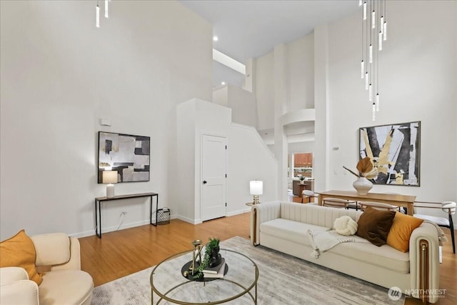 living area with baseboards, a high ceiling, and wood finished floors