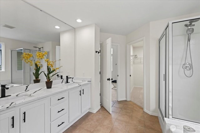 bathroom with visible vents, double vanity, a stall shower, and a spacious closet