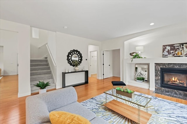 living room with baseboards, wood finished floors, stairway, and a high end fireplace
