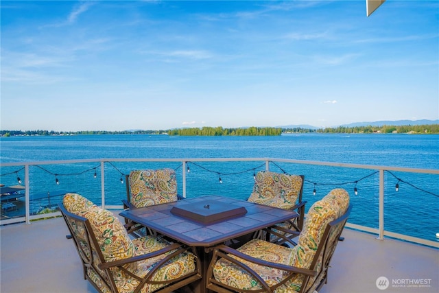 balcony with outdoor dining space and a water view