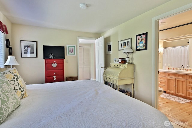bedroom with a sink, light wood finished floors, and ensuite bath