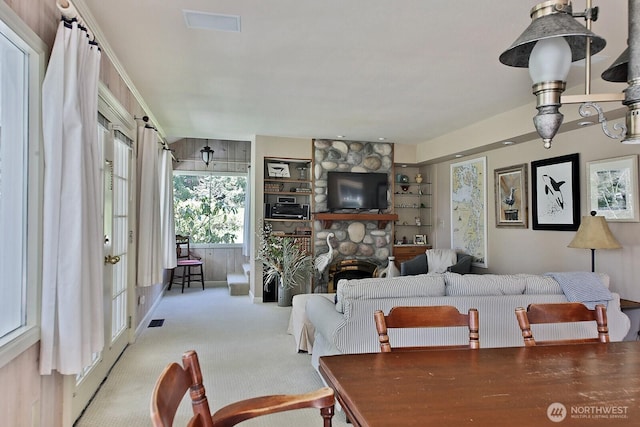 dining space with carpet floors, visible vents, built in shelves, and a fireplace