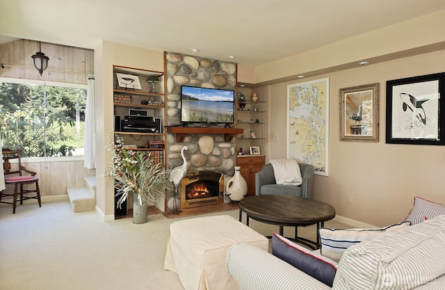sitting room featuring carpet floors, baseboards, a stone fireplace, and built in features