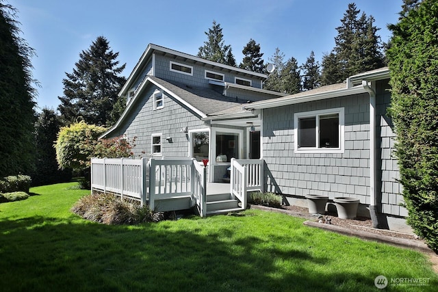 back of house with roof with shingles, a yard, and a deck