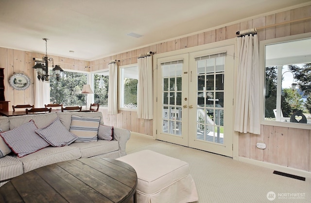 living area with wooden walls, carpet flooring, and french doors