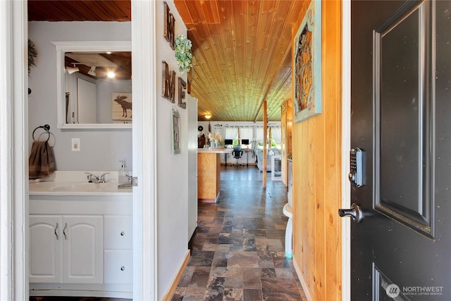 hallway with wood ceiling, stone finish flooring, and a sink