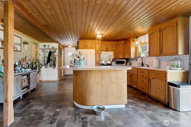 kitchen with a sink, wooden ceiling, backsplash, light countertops, and freestanding refrigerator