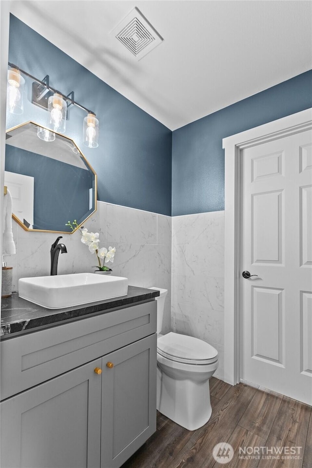 18431 Newport Dr, Arlington, WA 98223 - half bath with tile walls, wood finished floors, toilet, vanity, and wainscoting