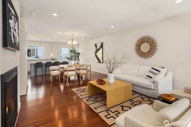 living room featuring dark wood-style flooring, recessed lighting, baseboards, and a chandelier