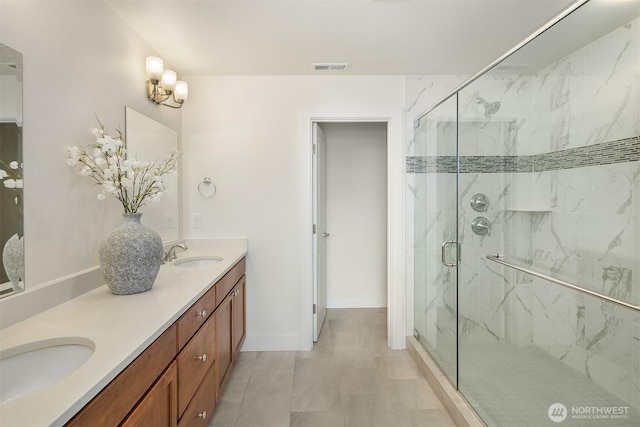bathroom featuring double vanity, visible vents, a marble finish shower, and a sink