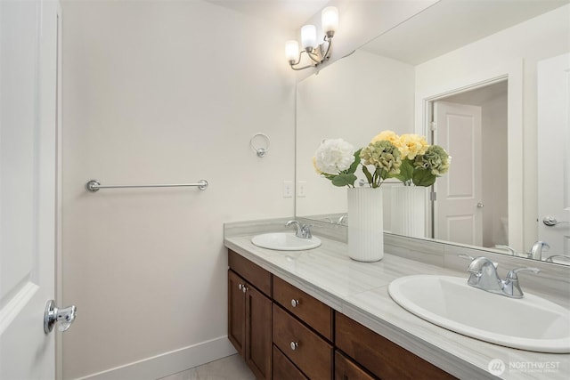 full bath with double vanity, a sink, baseboards, and toilet