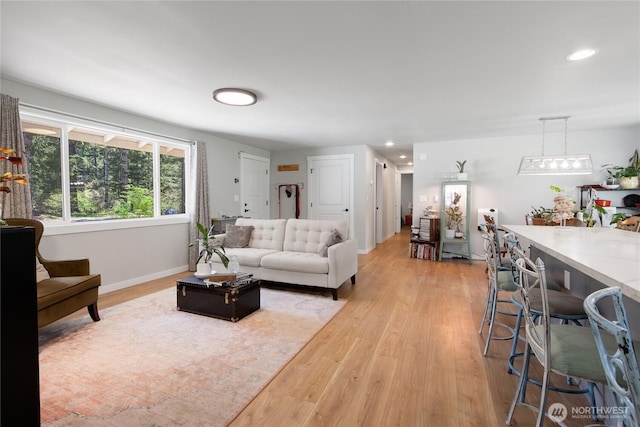 living room with baseboards, light wood-type flooring, and recessed lighting