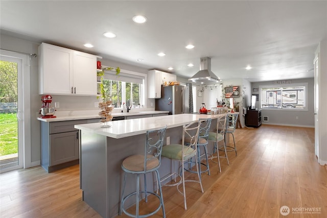 kitchen featuring a breakfast bar area, island range hood, freestanding refrigerator, and a wealth of natural light