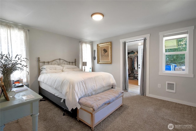 bedroom featuring carpet flooring, a walk in closet, and baseboards