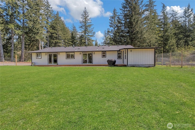 rear view of property with fence and a lawn