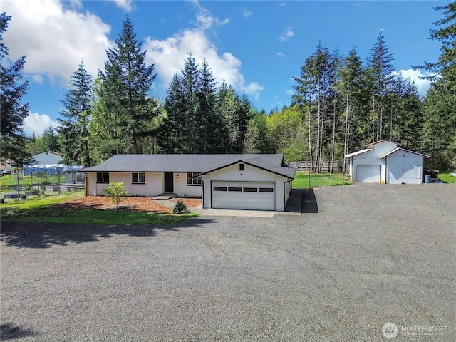 ranch-style house with fence, gravel driveway, and an outbuilding