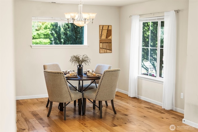dining space featuring baseboards, a notable chandelier, and wood finished floors