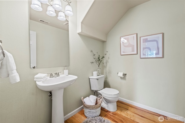 bathroom featuring toilet, wood finished floors, visible vents, baseboards, and vaulted ceiling