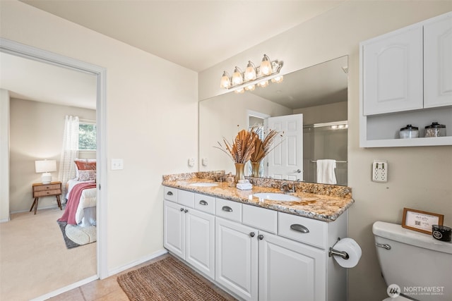 ensuite bathroom featuring a sink, double vanity, toilet, and ensuite bathroom