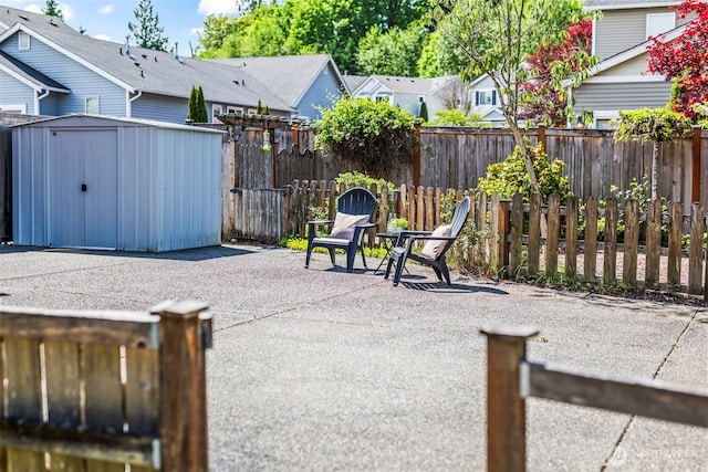 view of patio / terrace featuring an outdoor structure, a residential view, a fenced backyard, and a shed