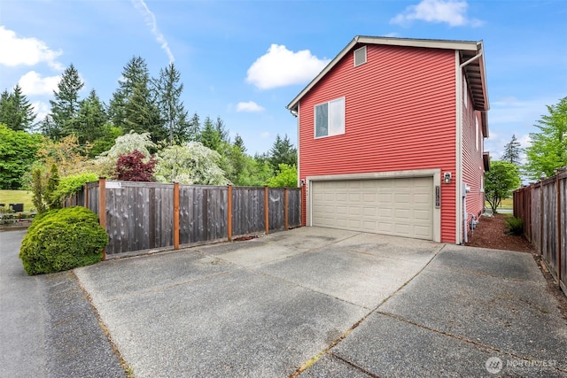 view of side of property featuring an attached garage and fence