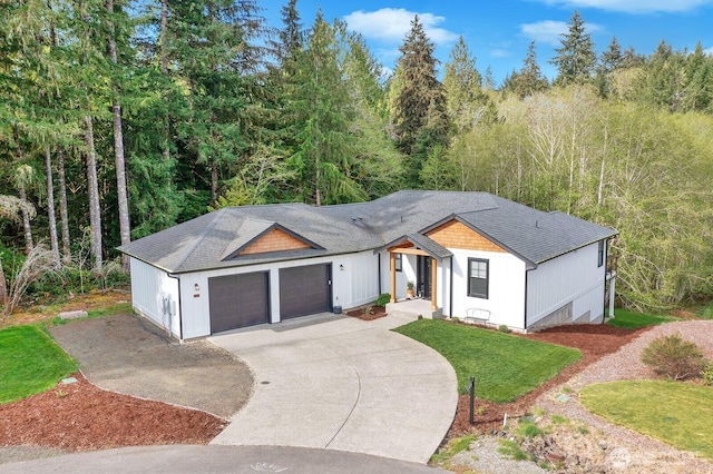 view of front facade with an attached garage, a front lawn, roof with shingles, and concrete driveway