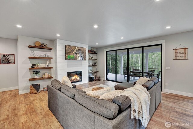 living room featuring baseboards, a fireplace, and recessed lighting