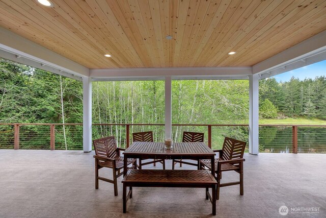 sunroom / solarium with recessed lighting, a view of trees, wood ceiling, and outdoor dining space