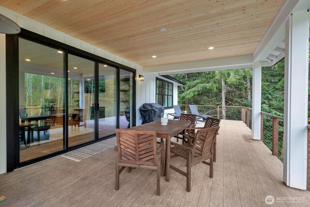sunroom featuring wood ceiling, wood finished floors, outdoor dining space, and a wall of windows