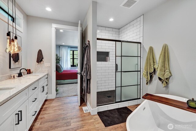 ensuite bathroom featuring a freestanding tub, visible vents, a shower stall, and a sink