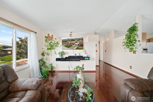 living area featuring baseboards, a ceiling fan, lofted ceiling, and wood finished floors