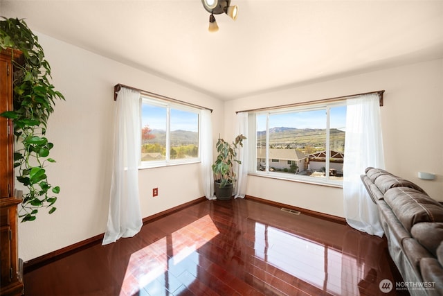 empty room with baseboards, a mountain view, and dark wood-style floors