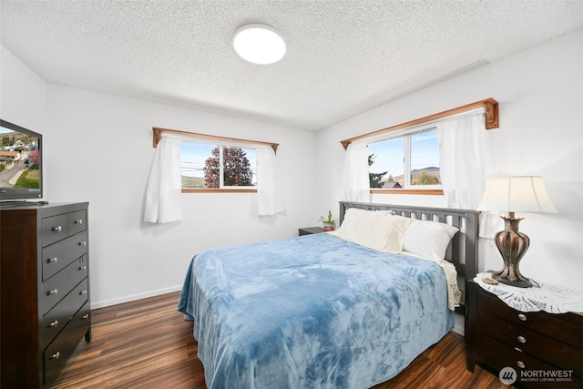 bedroom with baseboards, a textured ceiling, and dark wood-type flooring