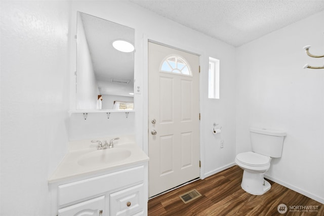 bathroom featuring vanity, toilet, a textured ceiling, wood finished floors, and visible vents