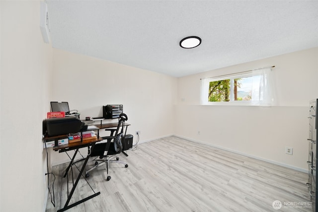 office featuring light wood-style floors, baseboards, and a textured ceiling