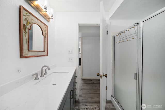full bathroom with a shower stall, wood finished floors, and vanity