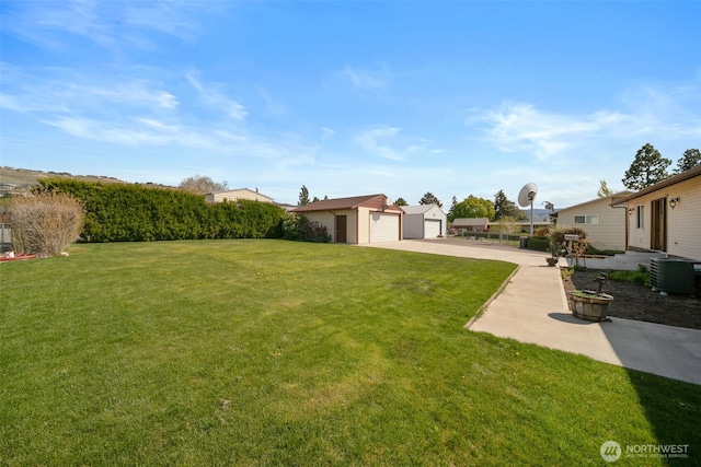 view of yard featuring a detached garage, an outbuilding, and cooling unit
