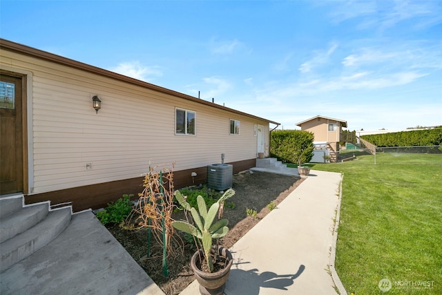 view of side of property featuring a yard, fence, central AC unit, and entry steps