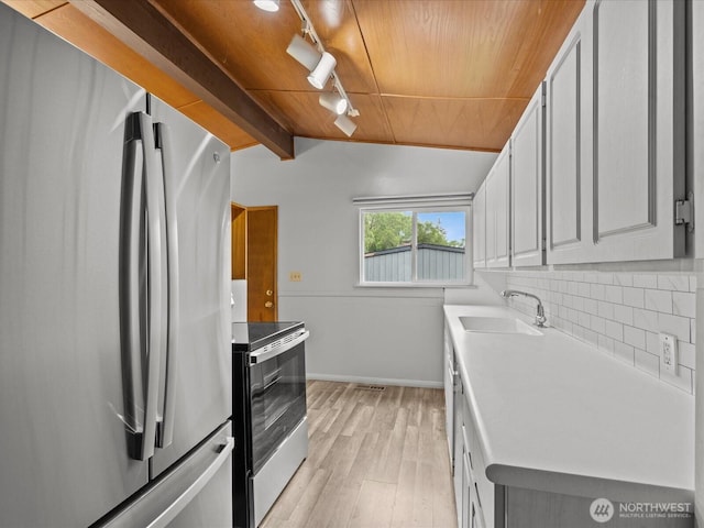 2909 SW 116th St, Burien, WA 98146 - kitchen with appliances with stainless steel finishes, a sink, rail lighting, light wood finished floors, and baseboards