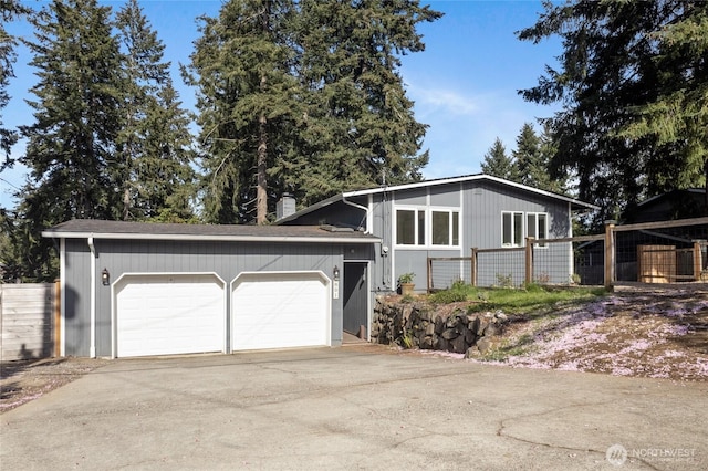 view of front facade with fence, an attached garage, and concrete driveway