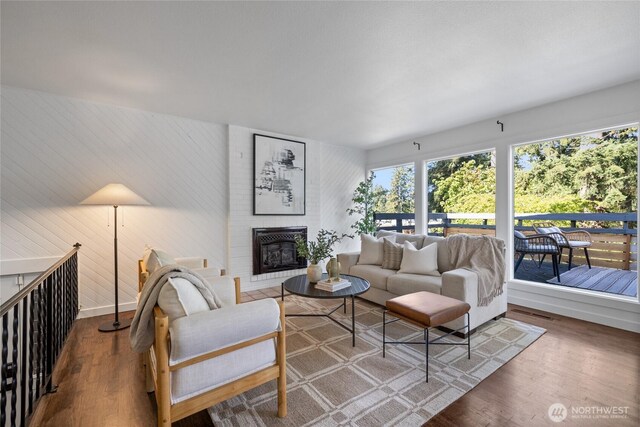 living area featuring a brick fireplace, wood finished floors, and wooden walls