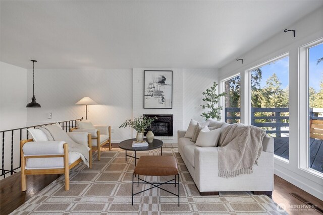 living area featuring visible vents, baseboards, a brick fireplace, and wood finished floors