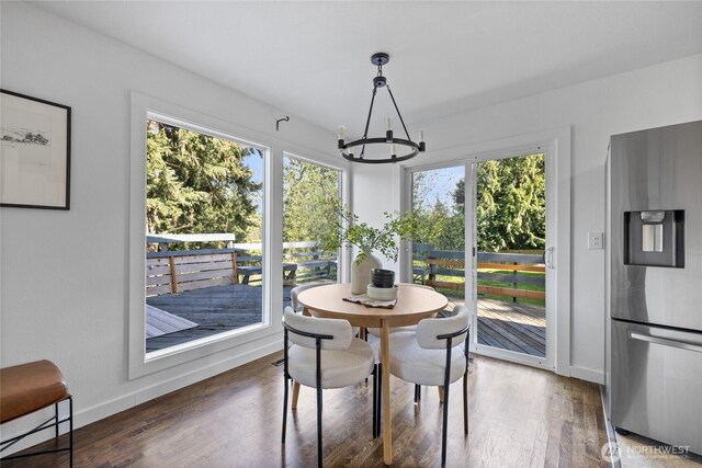 dining space with baseboards, wood finished floors, and a chandelier