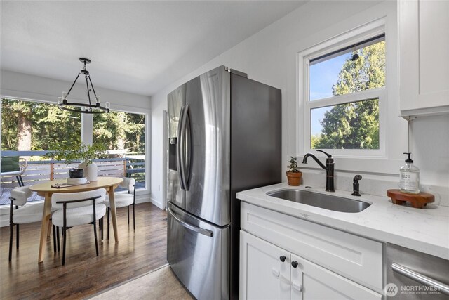 kitchen featuring light stone countertops, stainless steel fridge, a sink, and plenty of natural light