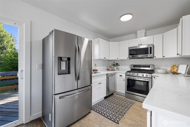 kitchen featuring light wood-style floors, appliances with stainless steel finishes, and white cabinets