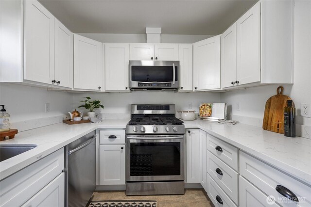 kitchen featuring appliances with stainless steel finishes, white cabinets, and light stone countertops