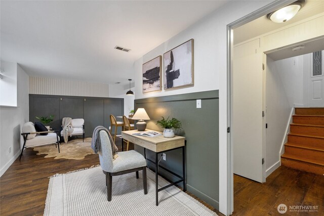 office with visible vents, an accent wall, baseboards, and wood finished floors