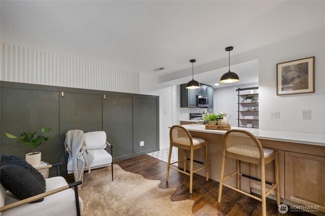 kitchen featuring visible vents, appliances with stainless steel finishes, light countertops, dark wood-style floors, and wallpapered walls