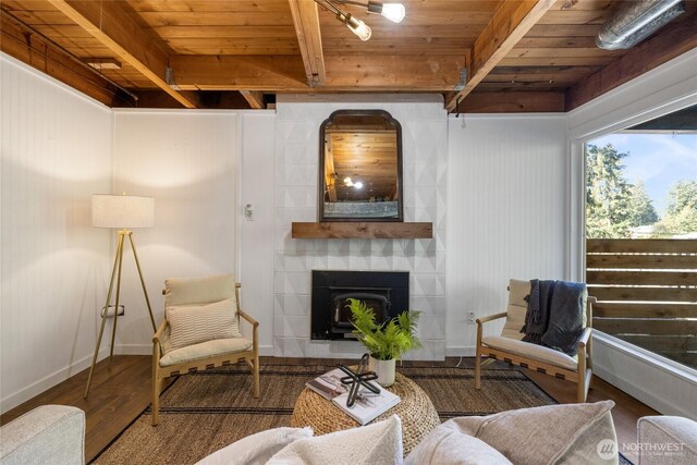 living room featuring a large fireplace, baseboards, wood finished floors, beamed ceiling, and wood ceiling